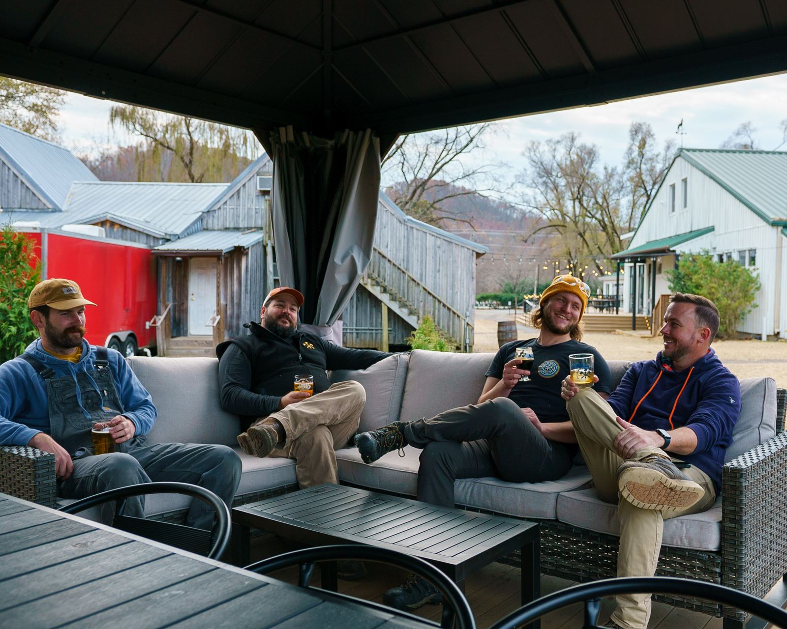 Friends with drinks on an outdoor sectional under a cabana